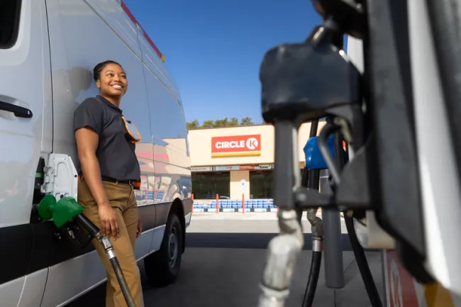 woman leaning against her van while fueling at Circle K